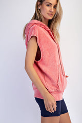 woman wearing a coral sleeveless hoodie with a front zipper, paired with navy bike shorts