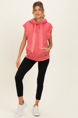 woman wearing a coral sleeveless maternity hoodie with a front pocket and black leggings