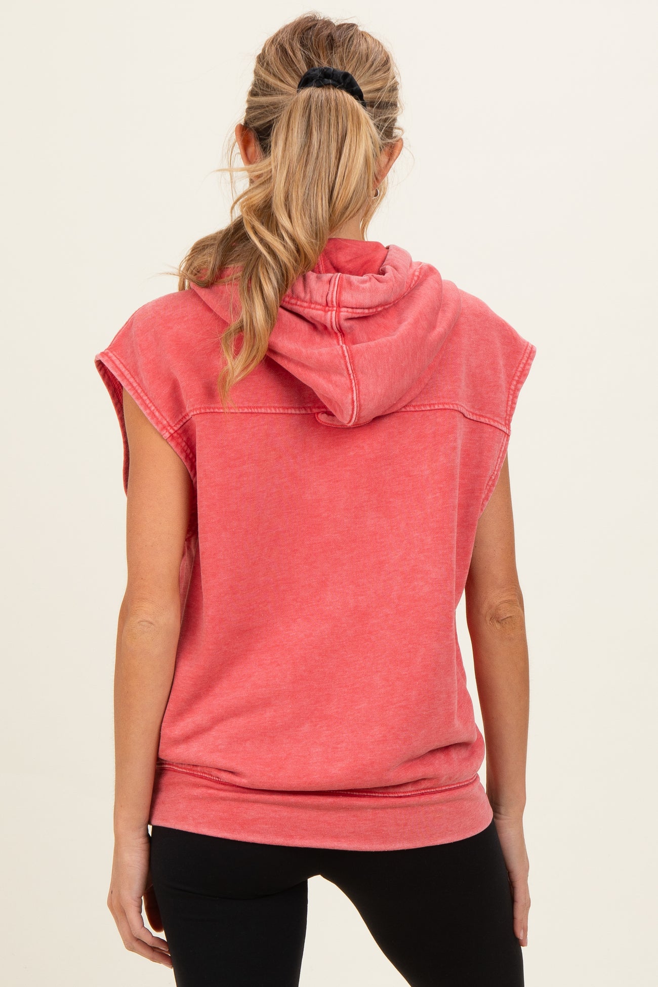 woman wearing a red sleeveless hoodie with a hood, styled for maternity wear