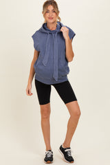 woman wearing a blue sleeveless maternity hoodie with a hood and front pocket, paired with black bike shorts