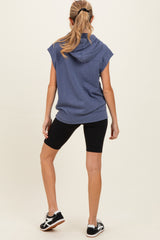 woman wearing a navy blue sleeveless maternity hoodie with a hood and black biker shorts from the back