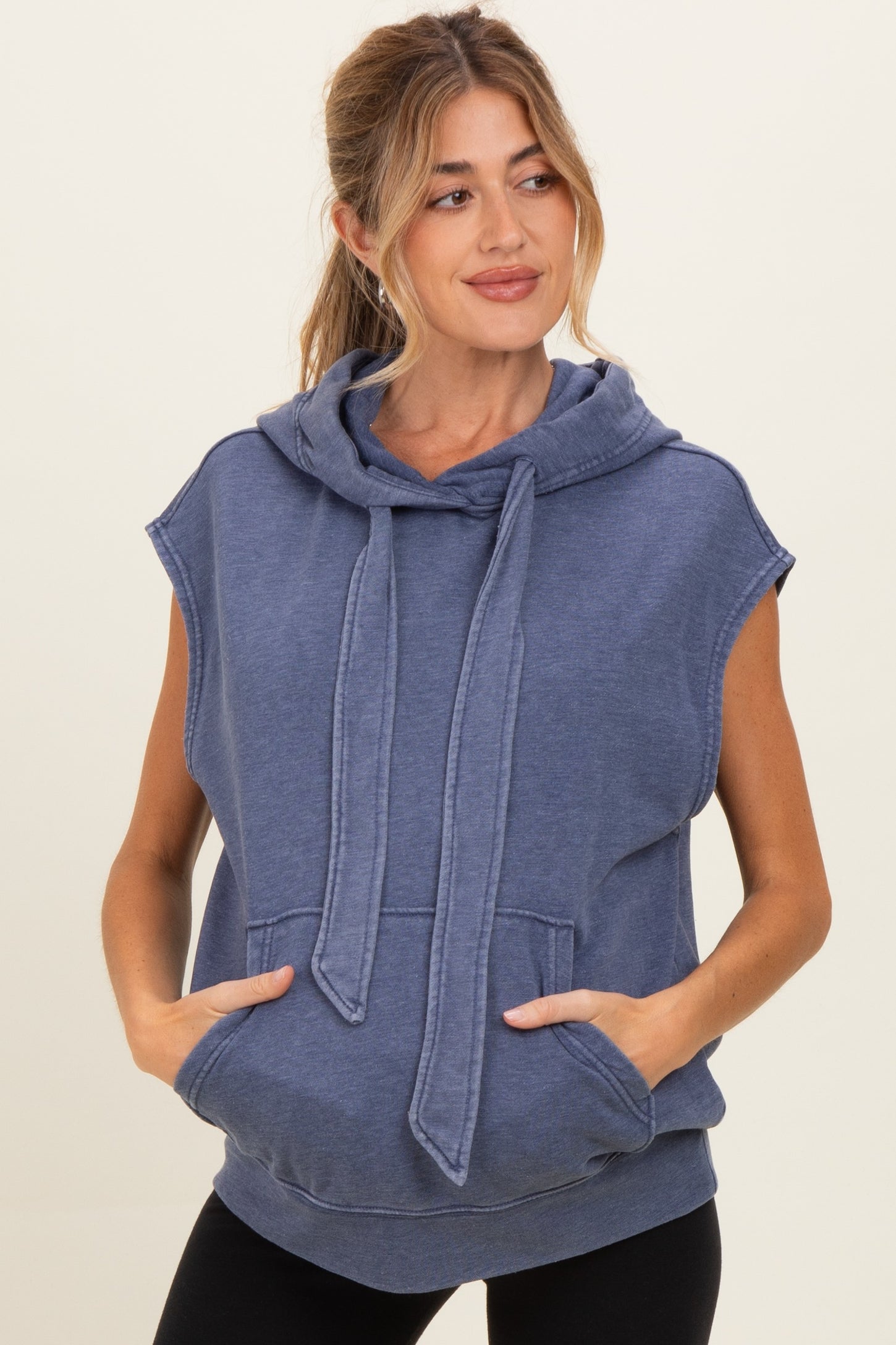 woman wearing a navy blue sleeveless hoodie with a drawstring and front pockets, maternity wear