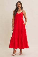 woman wearing a vibrant red maxi dress with adjustable straps and tiered skirt, featuring pockets and a fitted bodice