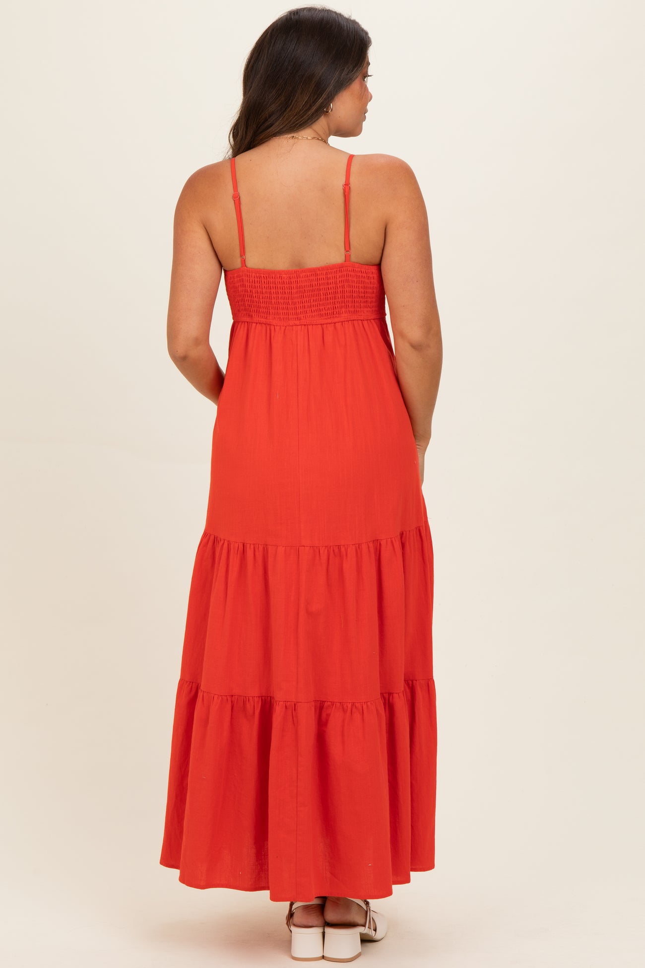 woman wearing a red maternity maxi dress with a smocked bodice and tiered skirt, seen from the back
