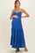 woman wearing a royal blue maternity maxi dress with a ruched bodice and tiered skirt, holding her baby bump