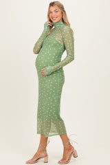 woman wearing a sheer green maternity dress with white polka dots and long sleeves, showing her baby bump
