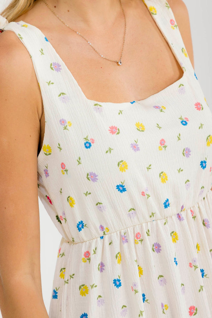 woman wearing a cream floral print sundress with square neckline and gathered waist detailing