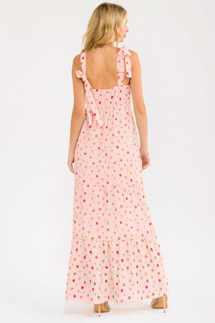 woman wearing a pink floral maxi dress with tie straps and a tiered hem, shown from the back