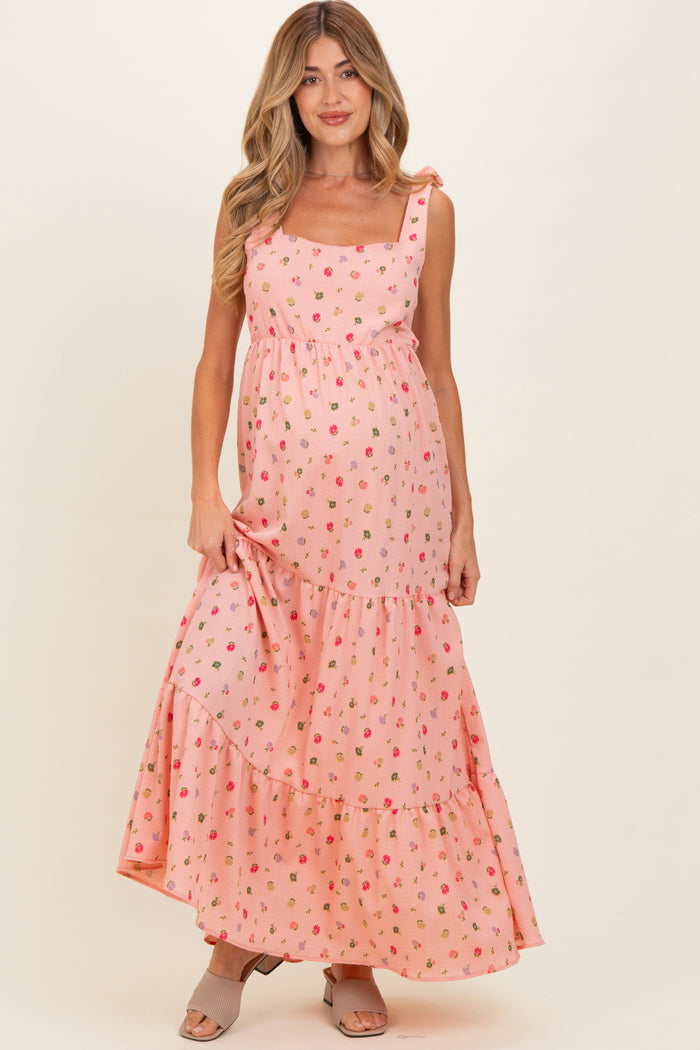 woman wearing a pink floral maternity maxi dress with tiered ruffles and a visible baby bump