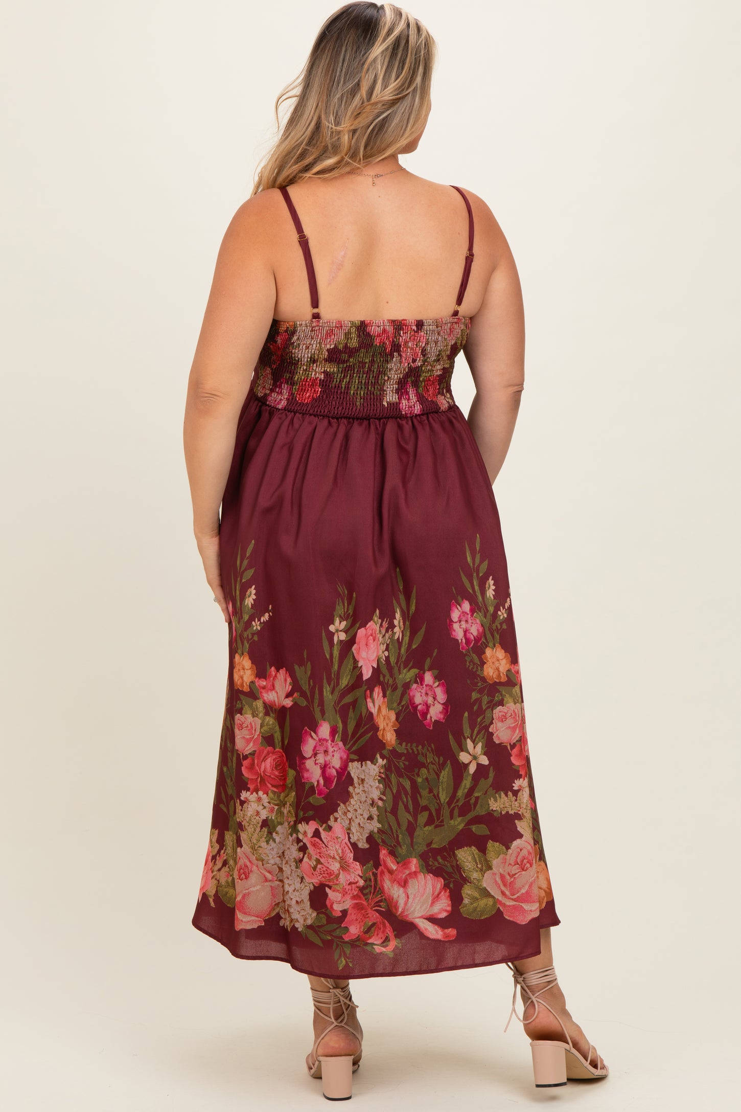 woman wearing a burgundy floral maxi maternity dress with a smocked bodice and adjustable straps, showing her baby bump