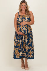 woman wearing a navy blue floral print maternity dress with spaghetti straps and holding her baby bump