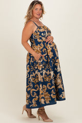 woman wearing a navy blue floral maternity maxi dress with adjustable straps and pockets, showcasing her baby bump