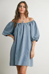 woman wearing a light blue off-the-shoulder denim dress with puff sleeves and a drawstring detail
