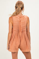 woman wearing a rust-colored maternity romper with pleated back detail