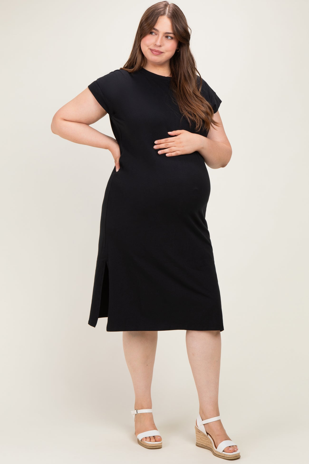 woman wearing a black short sleeve maternity dress with side slits and a visible baby bump