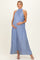 woman wearing a light blue halter neck maternity dress, standing and cradling her baby bump