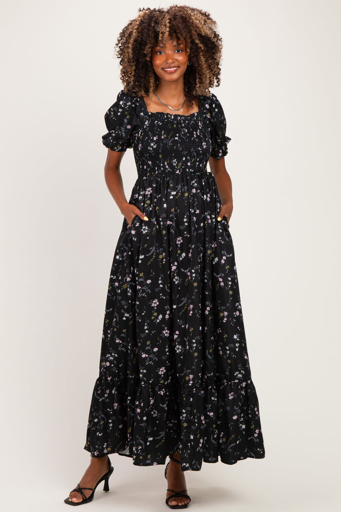 woman wearing a black floral print maternity maxi dress with puff sleeves and pockets