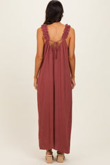 woman wearing a rust-colored maxi dress with ruffle straps and an open back detail