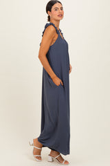 woman wearing a navy blue sleeveless maxi dress with ruffled details and side pockets