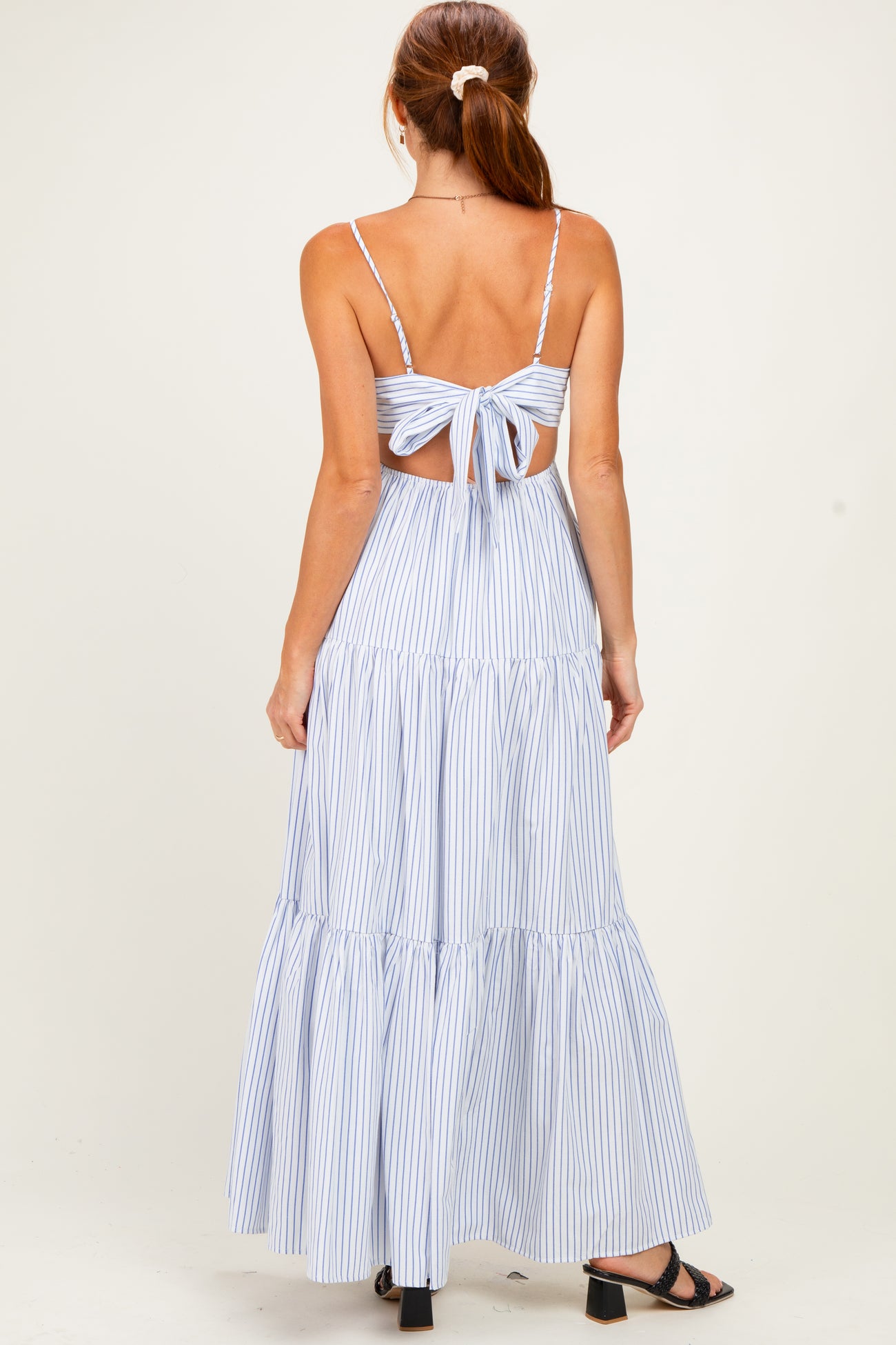 woman wearing a blue and white striped maxi dress with a back tie detail and tiered skirt