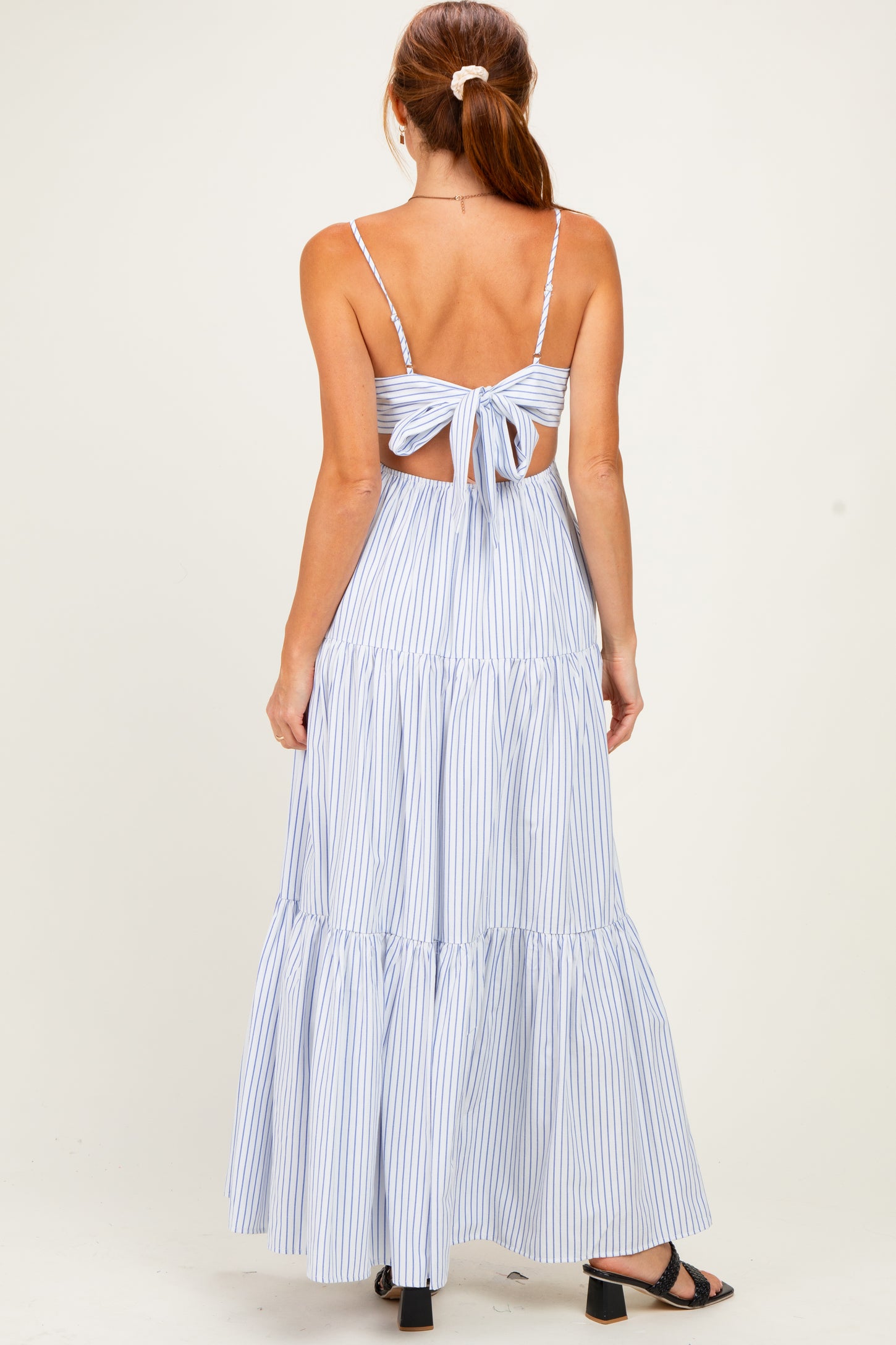 woman wearing a blue and white striped maxi dress with a back tie detail and tiered skirt