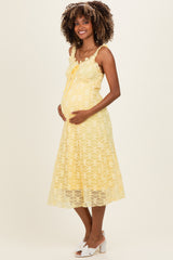 woman wearing a yellow lace maternity dress with straps and a flowy skirt, showing her baby bump
