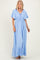 woman wearing a light blue maxi dress with flutter sleeves and a tie detail at the neckline
