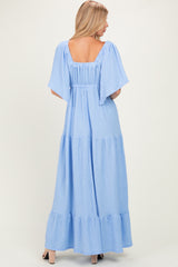 woman wearing a light blue maxi dress with short flutter sleeves and tiered ruffle hem, shown from the back