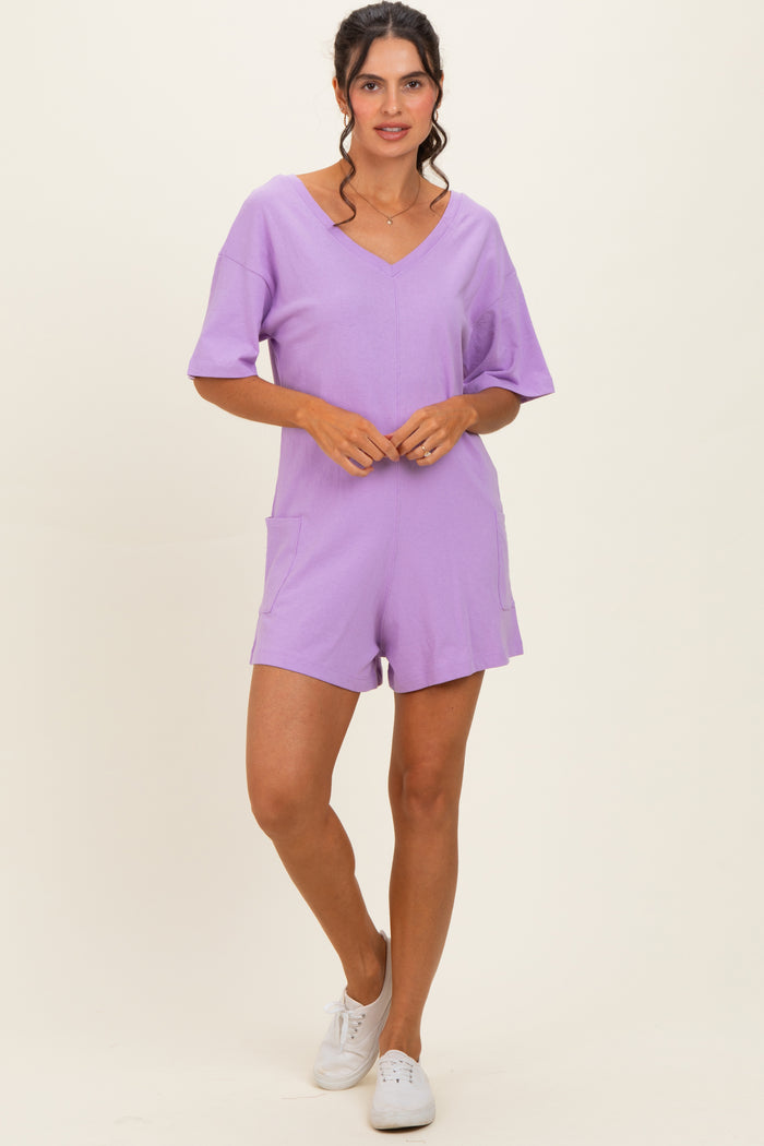 woman wearing a lavender short sleeve romper with a v-neckline and pockets, standing against a neutral background