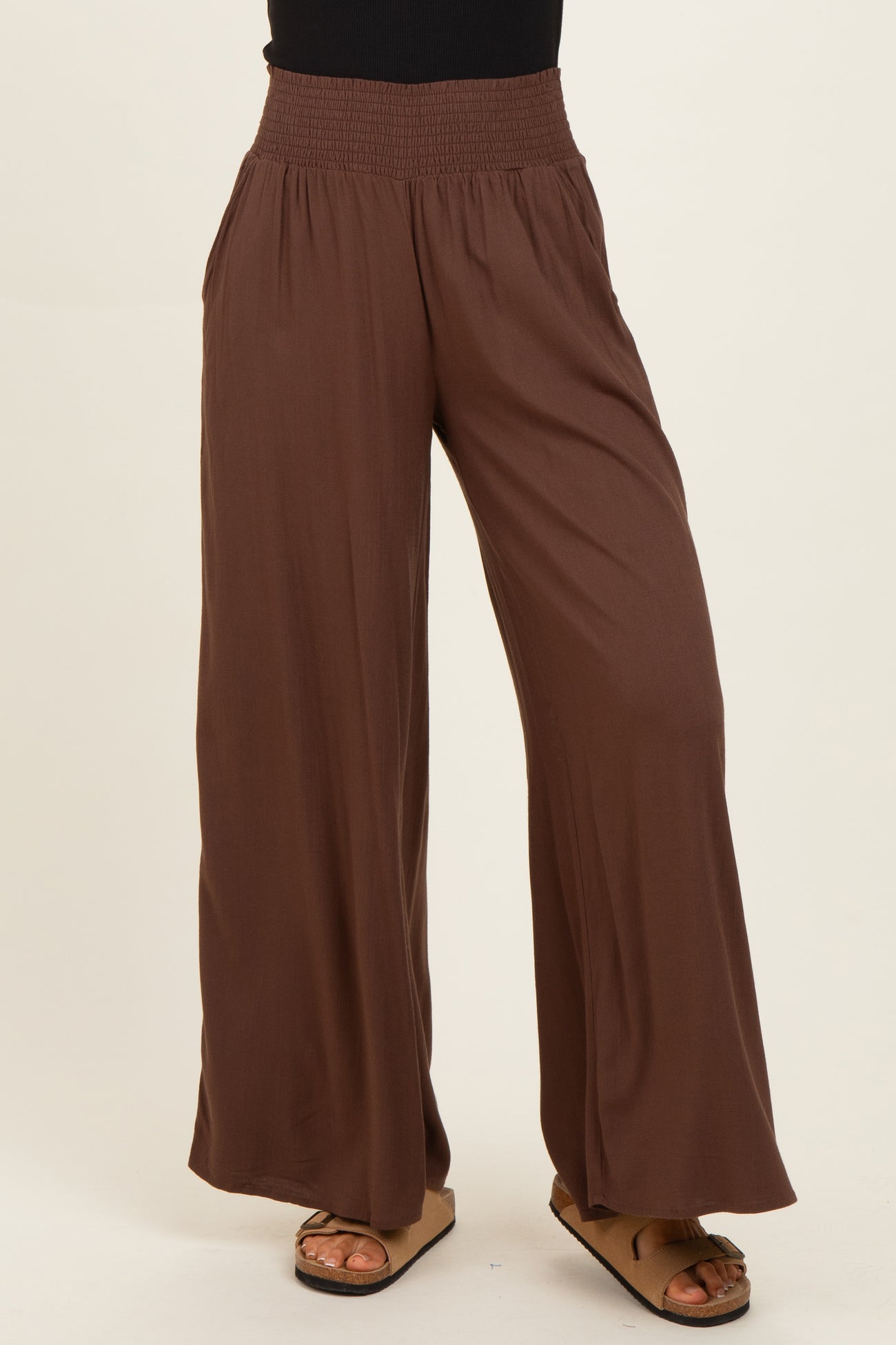 woman wearing brown wide-leg pants with a smocked waistband and side pockets
