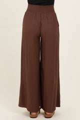 woman wearing brown wide-leg pants with a smocked waistband and side pockets, shown from the back
