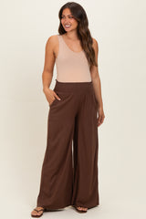 woman wearing a beige tank top and brown wide-leg maternity pants with a smocked waistband and pockets