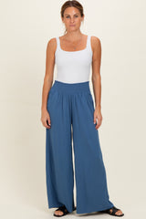woman wearing a white sleeveless top and blue wide-leg pants with a smocked waistband