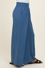 woman wearing blue wide leg trousers with a smocked waist and side pockets