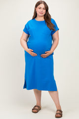 woman wearing a bright blue short sleeve maternity dress with a pocket, gently cradling her baby bump