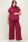 woman wearing a burgundy ribbed maternity top and wide-leg pants, holding her baby bump