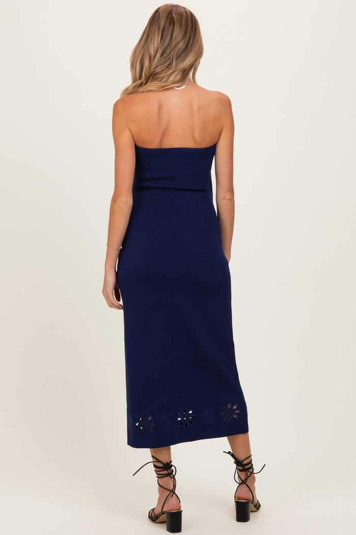 woman wearing a navy blue strapless maternity dress with floral cutout details at the hem