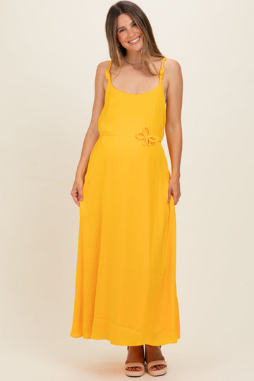 woman wearing a bright yellow maternity maxi dress with ruffle straps and a bow detail at the waist