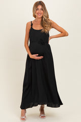 woman wearing a black maxi maternity dress with a bow detail and holding her baby bump