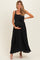 woman wearing a black maxi maternity dress with a bow detail and holding her baby bump