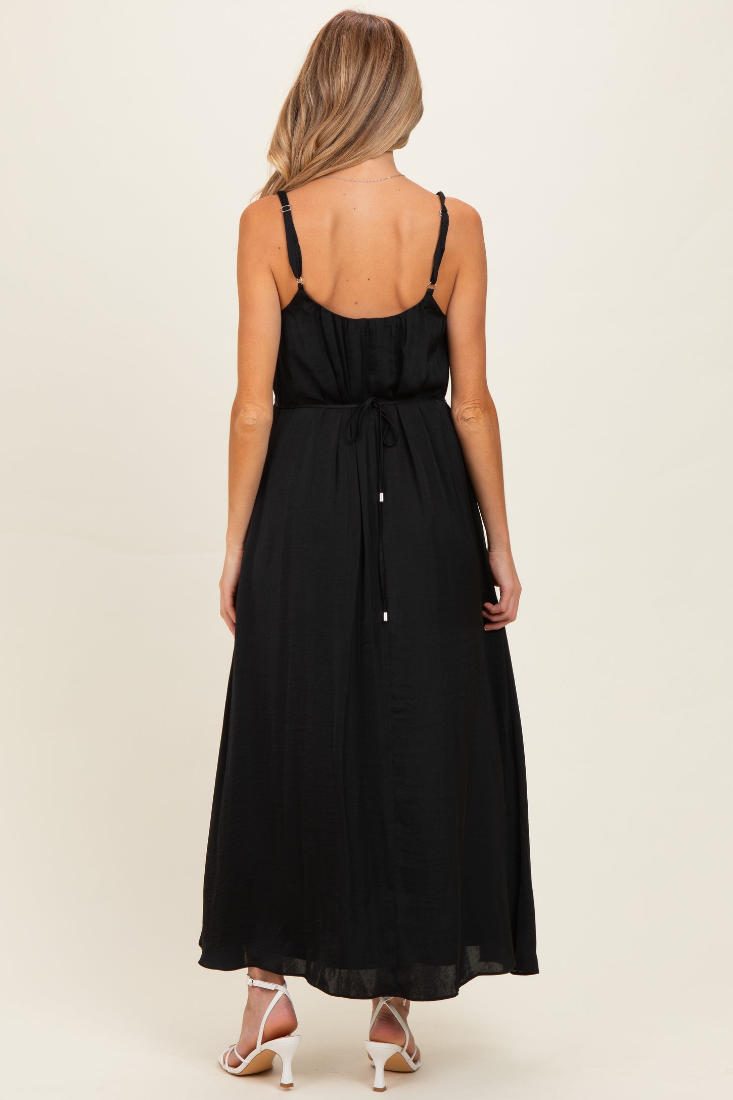 woman wearing a black maternity maxi dress with adjustable straps and a tie-back detail