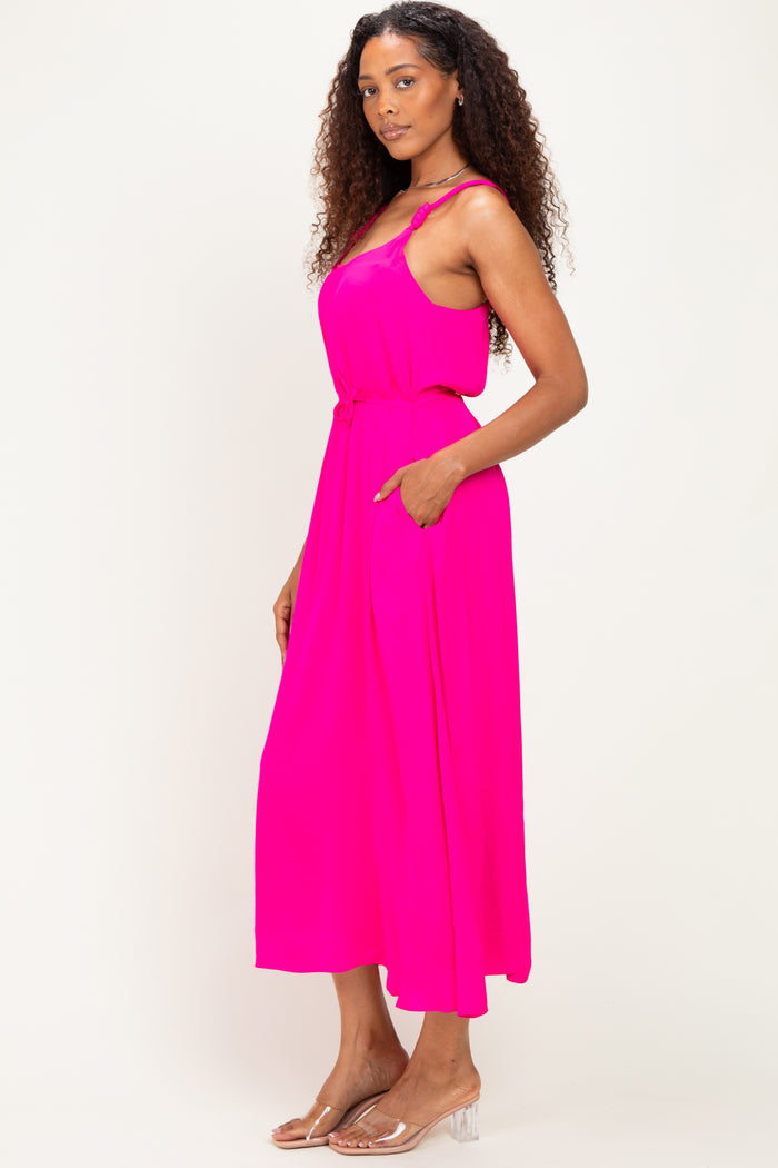 woman wearing a bright pink sleeveless maxi dress with a relaxed fit and side pockets