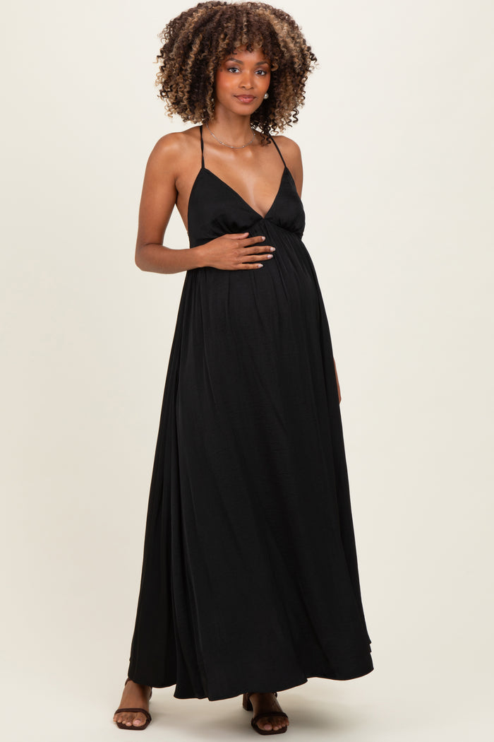 woman wearing a black halter maternity maxi dress and gently holding her baby bump