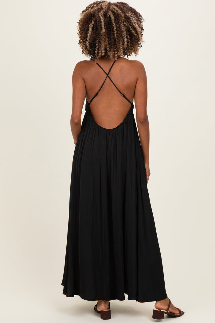 woman wearing a black maternity maxi dress with a cross-back design and open back