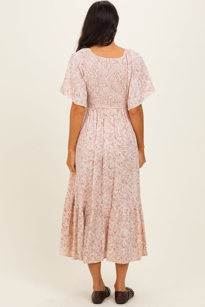 woman wearing a pink floral midi dress with short flutter sleeves and a smocked bodice, seen from the back
