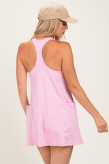 woman wearing a light pink sleeveless dress with back pockets and a beige cap
