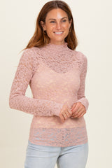 woman wearing a light pink lace long sleeve top with a mock neck and sheer details over a matching cami, smiling