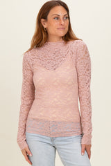 woman wearing a pink long sleeve lace top with a high neckline and a fitted silhouette, styled with light blue jeans