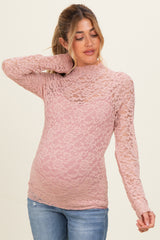 woman wearing a pink lace maternity top with a fitted style and long sleeves, showcasing her baby bump