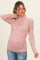 woman wearing a pink lace maternity top with a fitted style and long sleeves, showcasing her baby bump